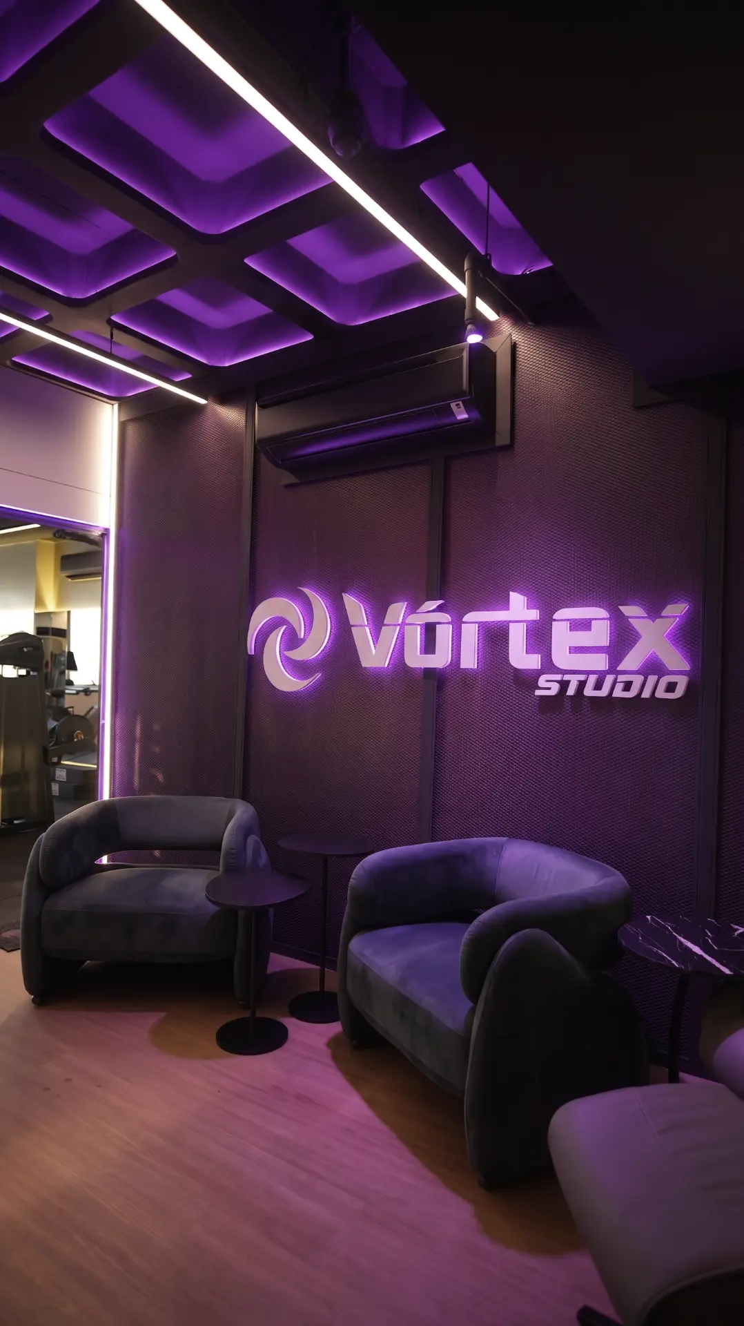Recepção do Estúdio Vórtex com logotipo iluminado e lounge premium